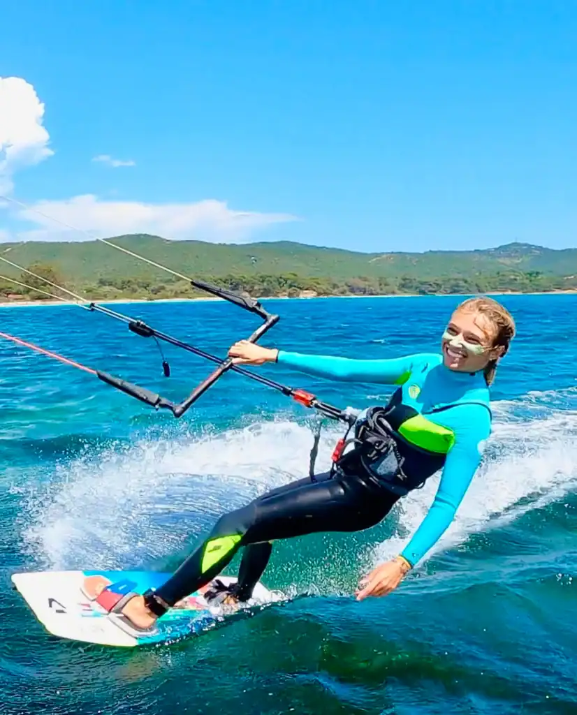Qui suis-je 3 Prête à naviguer, femme en combinaison de kitesurf sur la mer avec paysage côtier en arrière-plan.