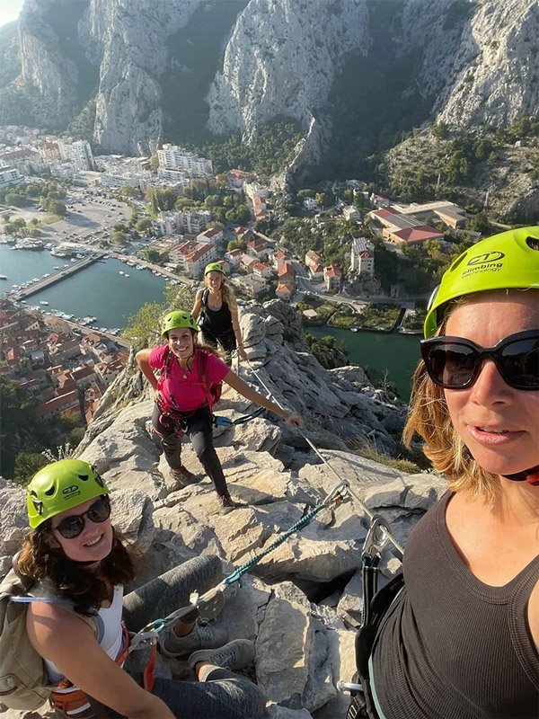 Escalade en groupe avec vue imprenable sur un canyon et une ville, équipe de femmes équipées en matériel de sécurité, adventure, outdoor, team building.
